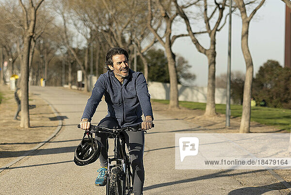 Happy mature man riding bicycle on road