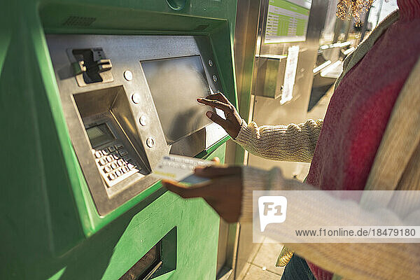 Junge Frau mit Kreditkarte am Geldautomaten