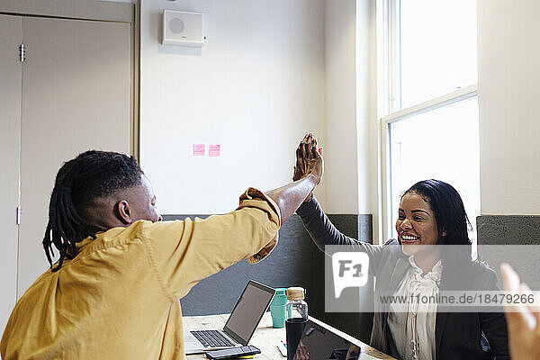 Businesswoman giving high-five to colleague at workplace