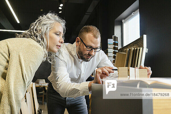 Zwei konzentrierte Kollegen arbeiten gemeinsam an einem Holzmodell im Architekturbüro
