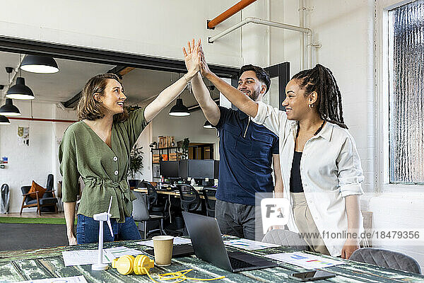 Happy business people doing high five in office