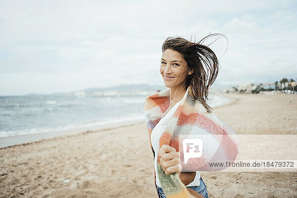 Smiling woman with scarf standing at beach