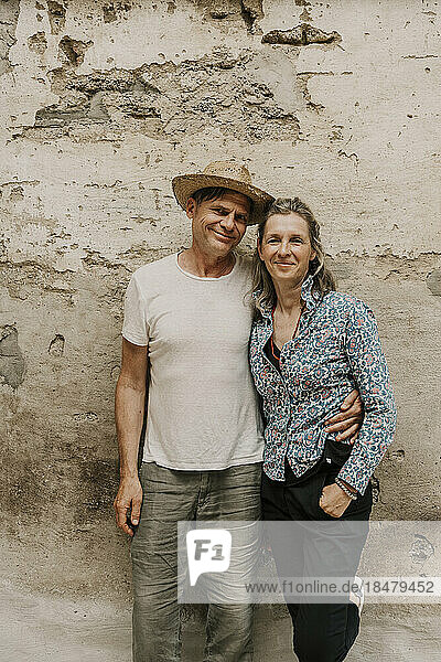 Smiling couple standing together in front of wall
