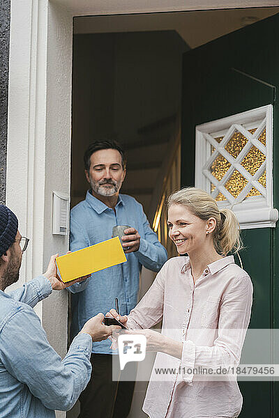 Delivery person giving package to customers at doorway