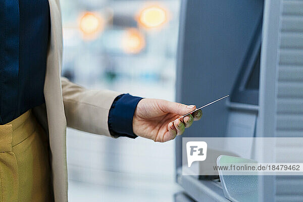 Hand of businesswoman holding credit card near ATM
