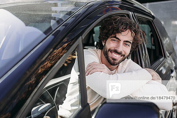 Happy young man leaning on car window