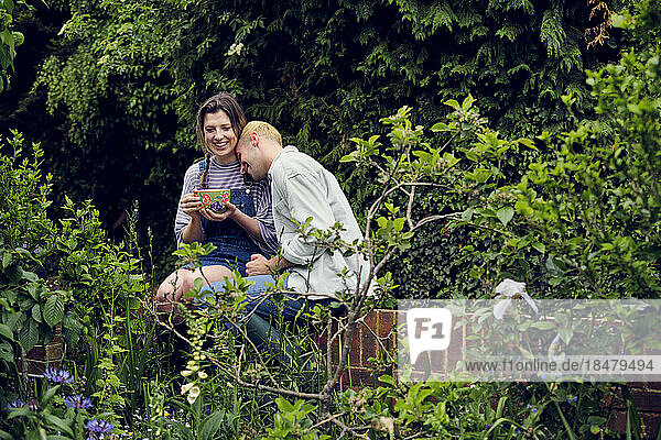 Glückliches Paar genießt es  gemeinsam auf dem Zaun im Hinterhof zu sitzen