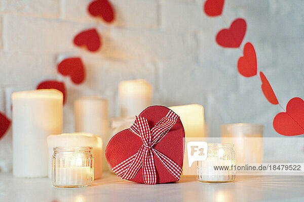 Heart shaped gift box with candles on table