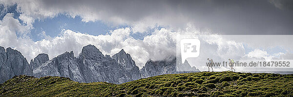 Man and woman hiking under cloudy sky at Forcella Venegia  Dolomites  Italy