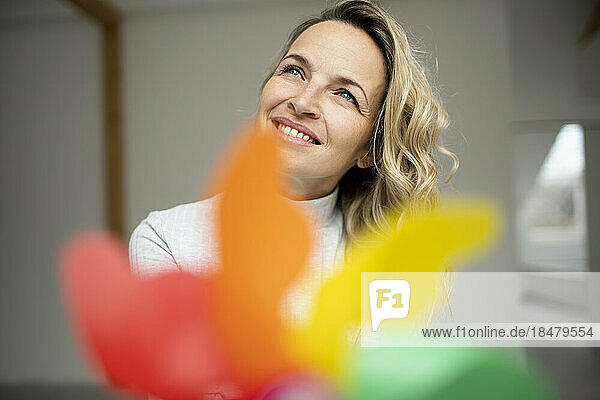 Happy mature woman with pinwheel toy day dreaming