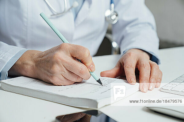 Doctor writing prescription with pen at desk