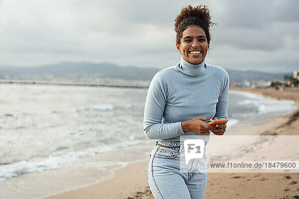 Happy young woman with smart phone at beach