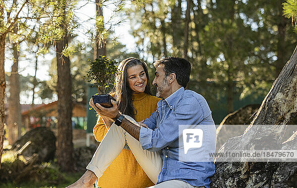 Smiling mature couple holding bonsai outdoors