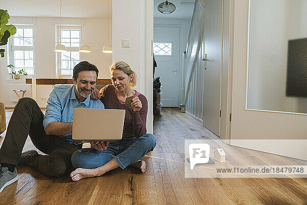 Mann und Frau erledigen Online-Einkäufe und sitzen zu Hause auf dem Boden