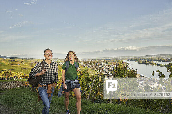 Happy tourists hiking by vineyard under sky