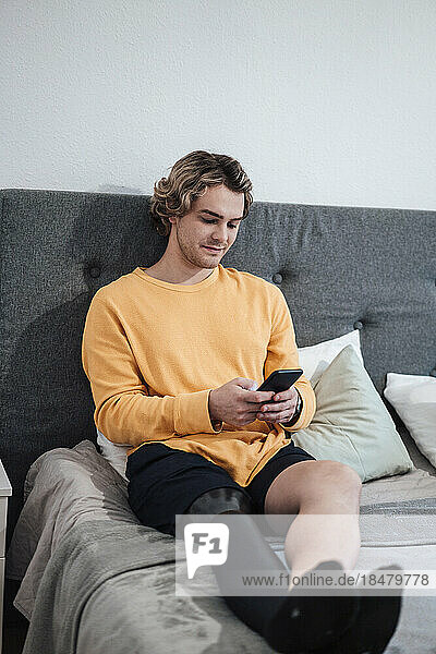 Man using smart phone on bed at home