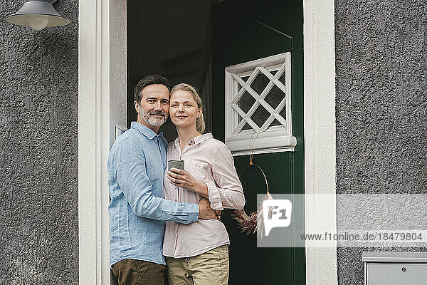 Mature man embracing wife at doorway of house