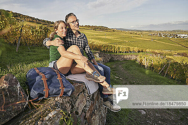 Contemplative mature couple sitting on wall in vineyard