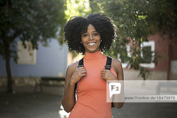 Glückliche junge Frau mit Afro-Frisur steht auf der Straße