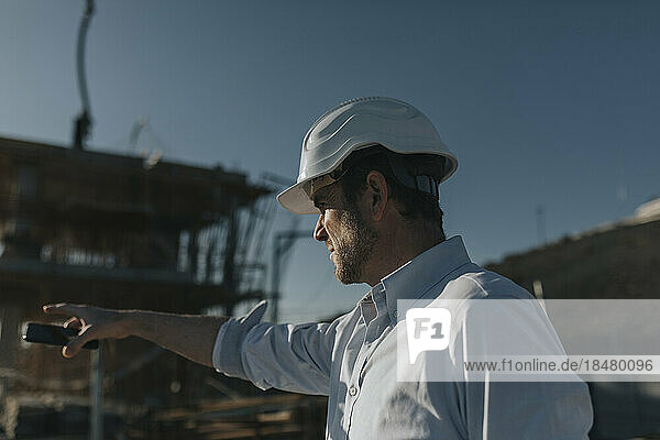 Architect gesturing in construction area on sunny day