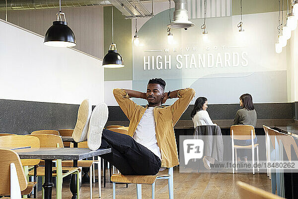 Businessman with hands behind head relaxing in cafeteria