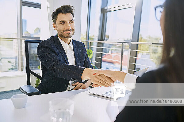 Smiling recruiter doing handshake with candidate at office