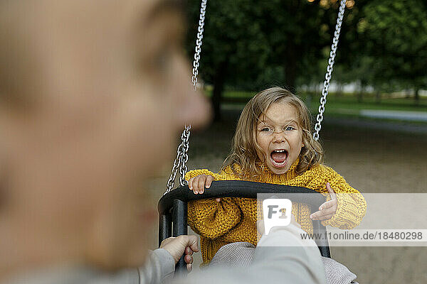 Father pushing daughter on swing at park