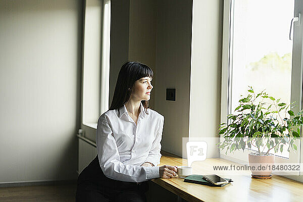 Brunette businesswoman looking out of window in office