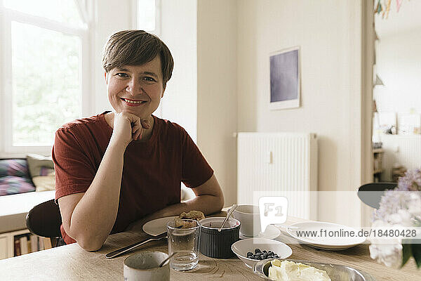 Happy woman with breakfast on dining table at home