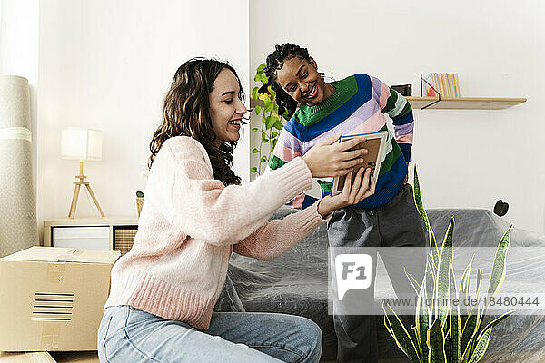 Young woman showing photo frame to friend at home