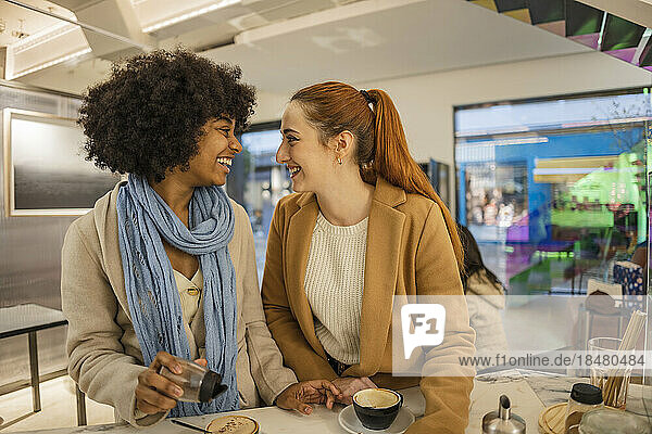 Fröhliche junge Freunde mit Kaffeetasse stehen am Tisch im Café