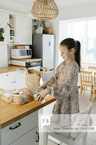 Girl unpacking groceries on kitchen island at home