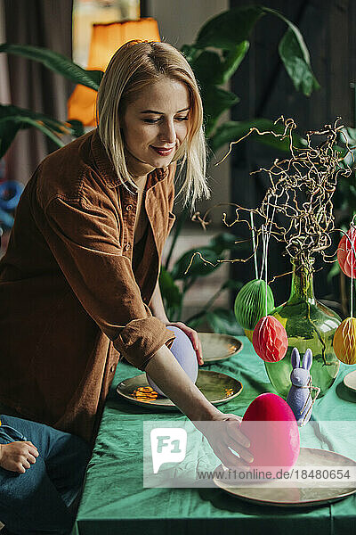 Smiling woman decorating Easter dinner table at home