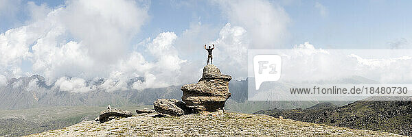 Mann steht mit erhobenen Armen am Elbrus unter bewölktem Himmel  Kaukasus