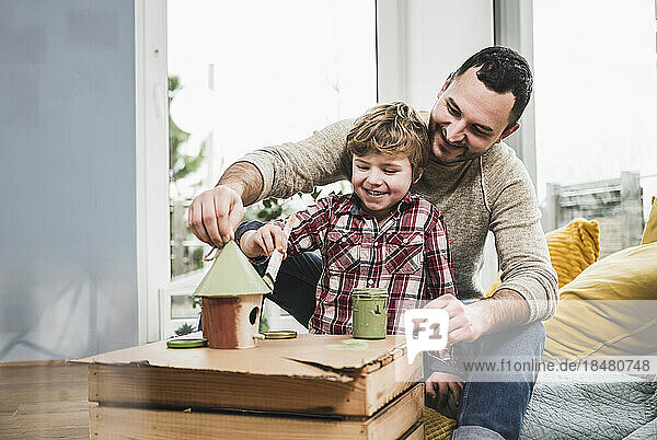 Happy father and son painting model house at home