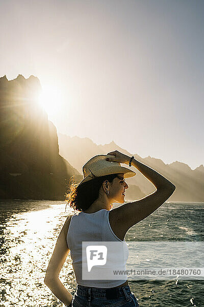 Spanien  Kanarische Inseln  junge Frau bewundert den Sonnenuntergang über den Küstenbergen des Macizo de Anaga-Gebirges