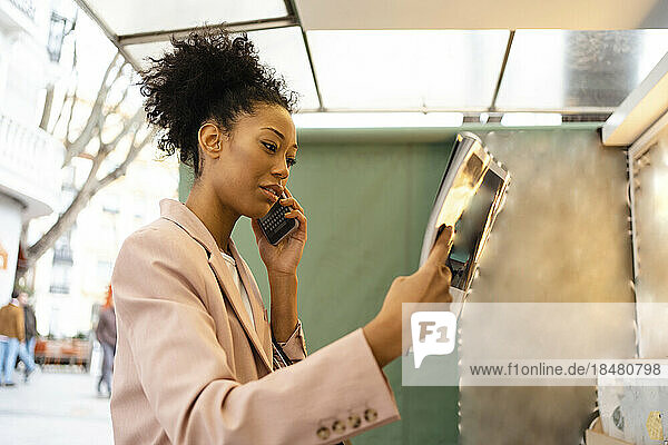 Businesswoman reading magazine and talking on smart phone