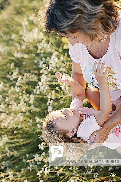 Happy girl with playful mother in summer field