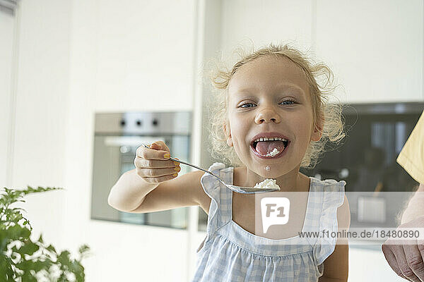 Girl tasting flour in kitchen at home
