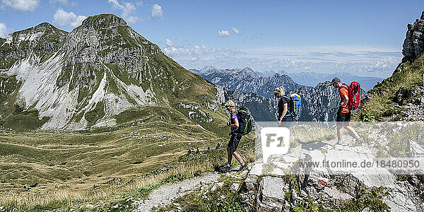 Man and women with backpack hiking towards Rifugio dal piaz on sunny day at Dolomites  Italy