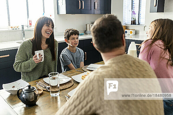 Happy mother and father having breakfast with children together at home