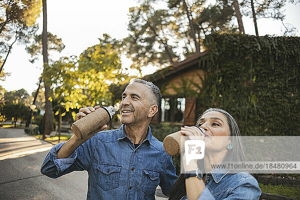 Mature couple drinking from reusable bottles on the road