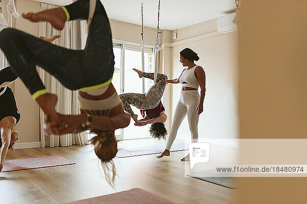 Instructor teaching aerial yoga to students in studio