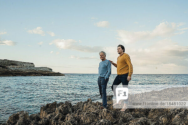 Mann steht mit Vater auf Felsen vor dem Meer