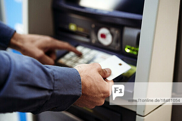 Businessman with credit card using ATM machine