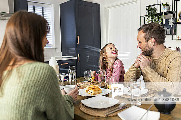 Fröhliches Mädchen mit Vater und Mutter beim Frühstück zu Hause