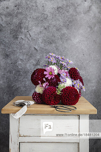 Blumenstrauß aus roten und rosa Saisonblumen auf dem Nachttisch