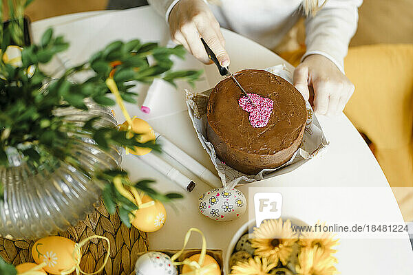 Hands of girl cutting Easter cake on table at home