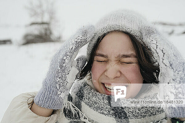 Cheerful teenage girl wearing knit hat enjoying in winter