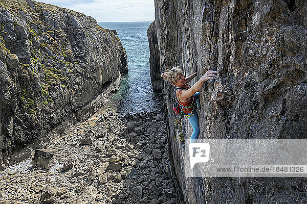 Mature athlete climbing rocky wall